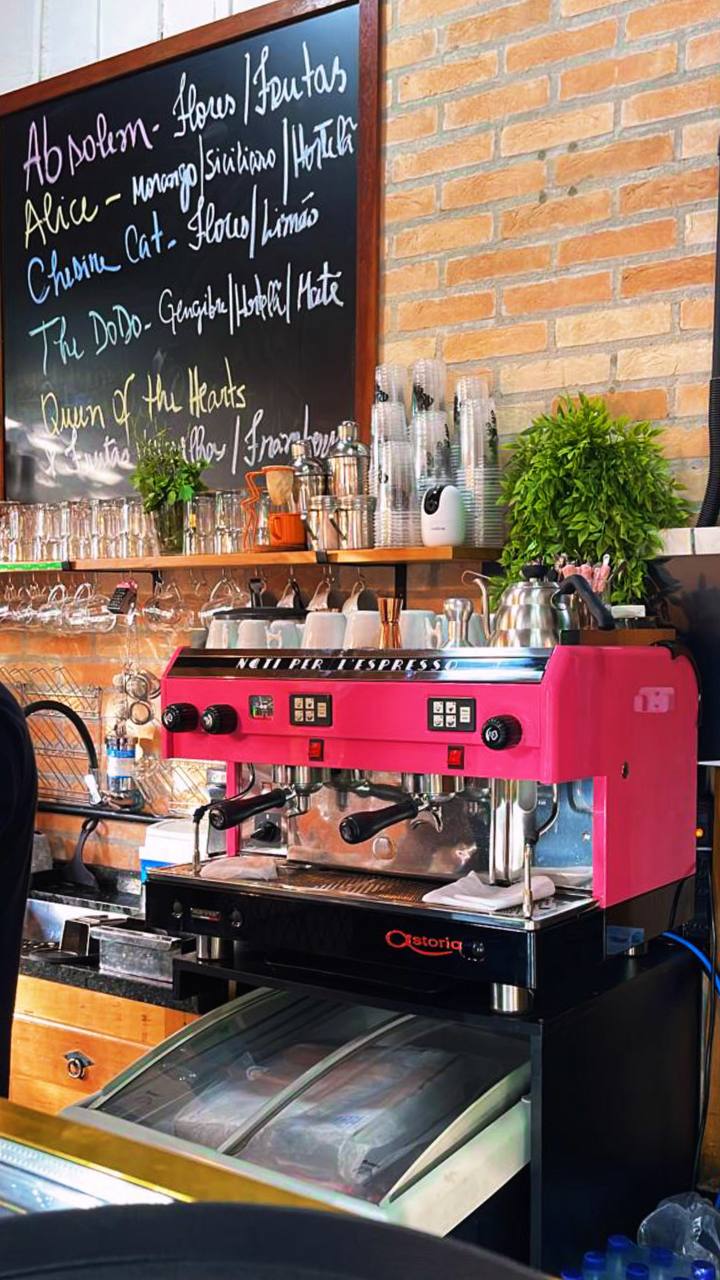 Máquina de espresso rosa Netti com menu de bebidas e plantas decorativas em café